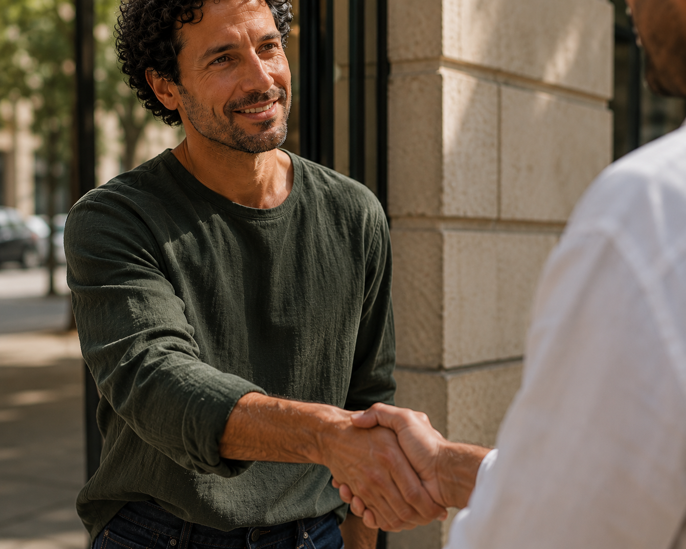 Antonio greeting a client with a handshake outside a sunlit boutique