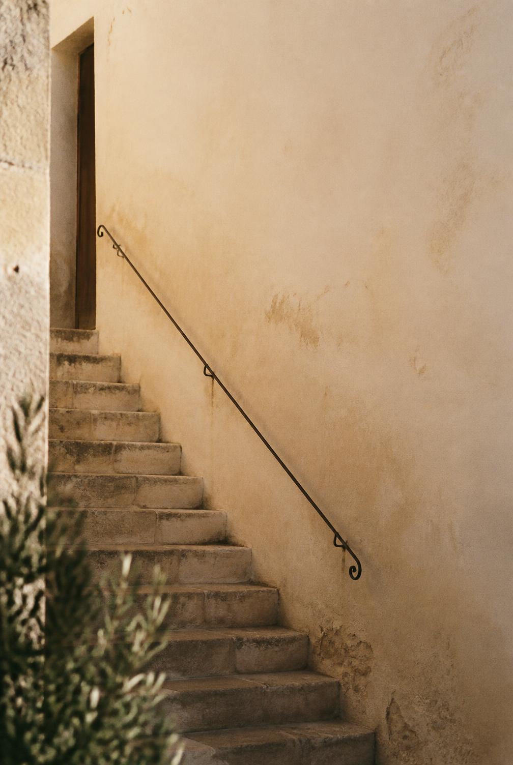 Stone staircase and iron handrail against a warm plaster wall in morning light
